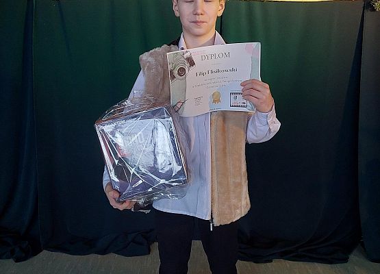 Nagrodzony uczeń prezentuje dyplom