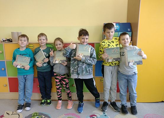 uczniowie stoją i trzymają wyprawki czytelnicze