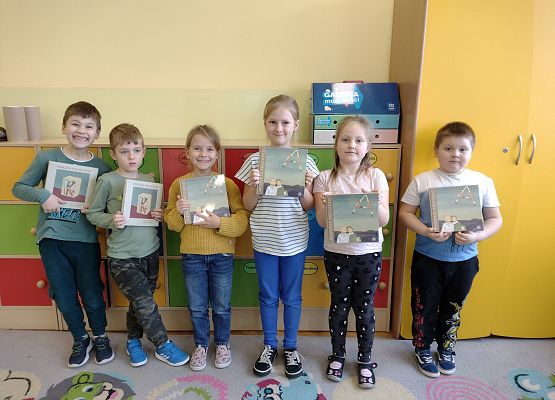 uczniowie stoją i trzymają wyprawki czytelnicze