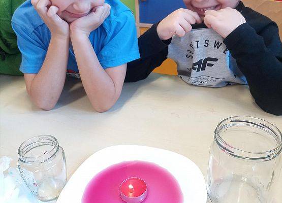 dzieci obserwują doświadczenie z gasnącą świeczką