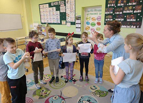 nauczycielka pokazuje dzieciom, jak zgnieść kartkę papieru