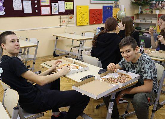 uczniowie jedzą pizzę