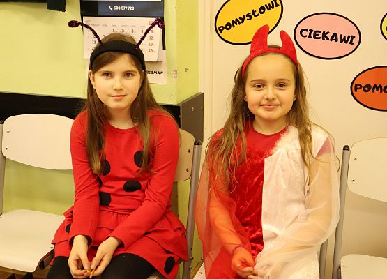 dwie dziewczynki w kolorowych strojach siedzą