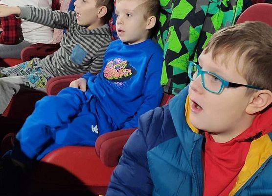 Dzieci siedzą na fotelach w sali kinowej