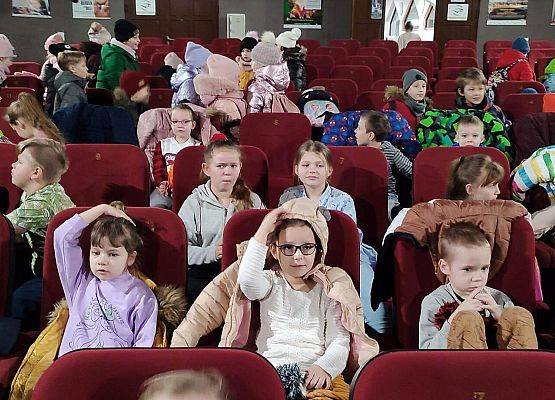 Dzieci siedzą na fotelach w sali kinowej