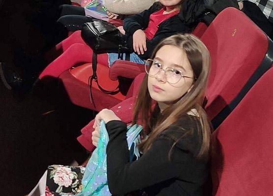 Dzieci siedzą na fotelach w sali kinowej