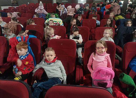 Dzieci siedzą na fotelach w sali kinowej