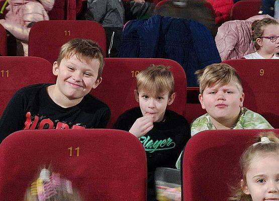 Dzieci siedzą na fotelach w sali kinowej