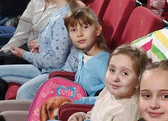 Dzieci siedzą na fotelach w sali kinowej
