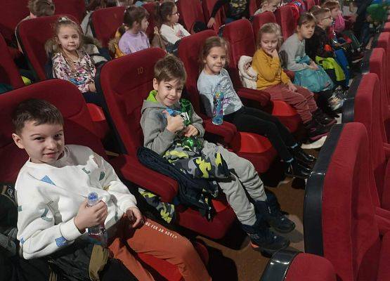 Dzieci siedzą na fotelach w sali kinowej