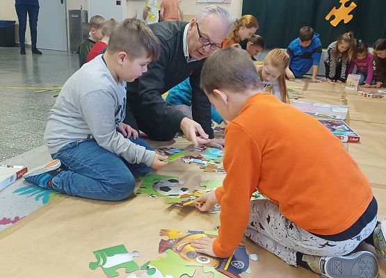 Dyrektor układa z dziećmi puzzle
