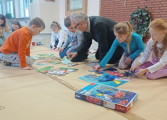 Dyrektor układa z dziećmi puzzle