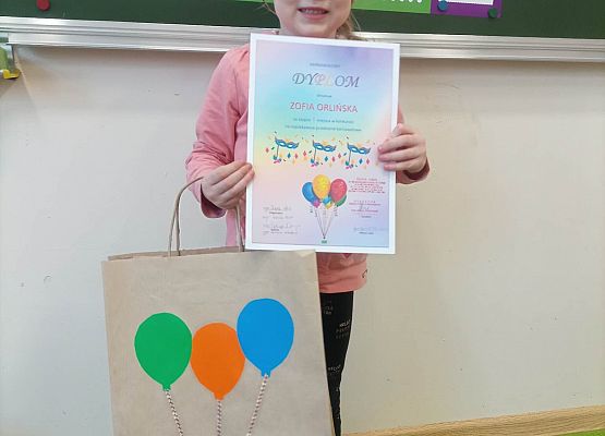 dziewczynka prezentuje otrzymany dyplom