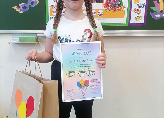 dziewczynka prezentuje otrzymany dyplom