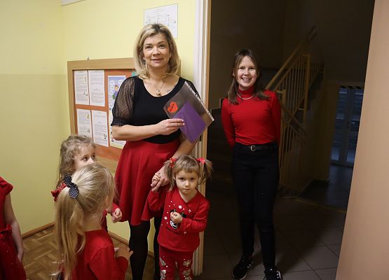 uśmiechnięta pani trzyma kartkę walentynkową, obok stoją dzieci