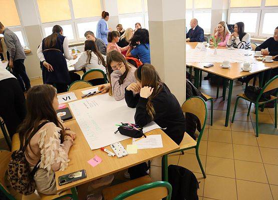 przedstawiciele samorządów uczniowskich siedzą przy stolikach i pracują w grupach