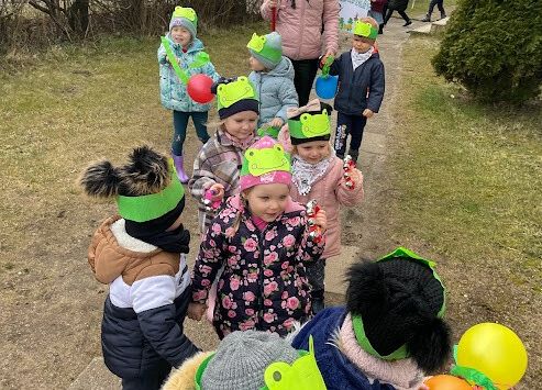 dzieci idą przywitać wiosnę, pani trzyma transparent z napisem witaj wiosno