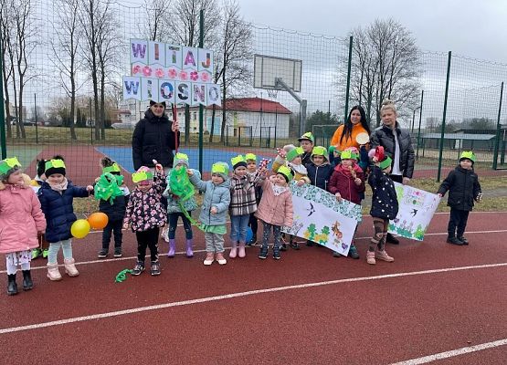 dzieci z nauczycielkami maszerują po szkolnym boisku