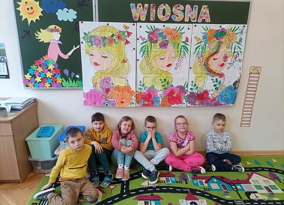 dzieci siedzą, nad nimi wiszą plakaty o wiośnie