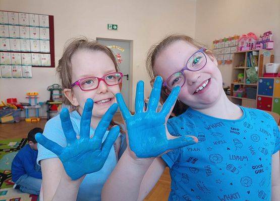 dwie dziewczynki machają niebieskimi dłońmi