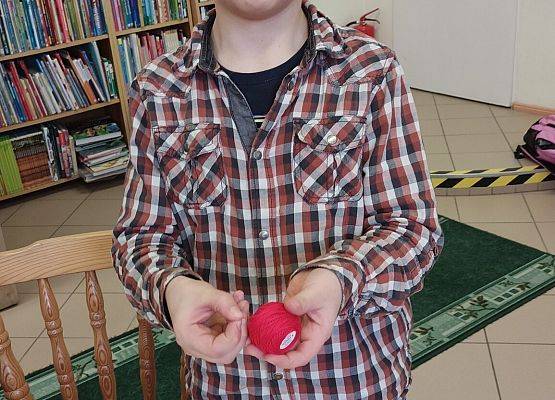 uczeń trzyma w dłoniach czerwony kłębek