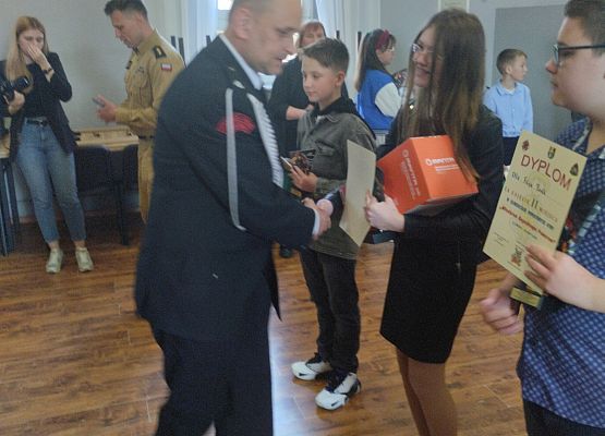 Strażak wręcza uczennicy nagrodę