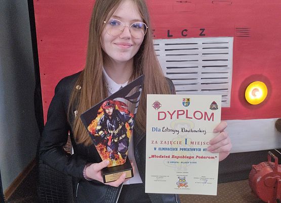 Uczennica prezentuje dyplom i statuetkę