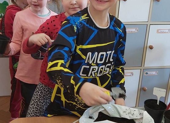 Chłopiec nabiera ziemię z worka