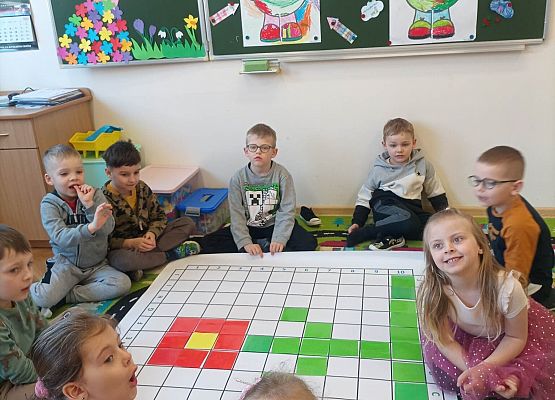 Dzieci siedzą przy macie do kodowania