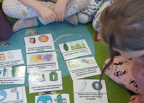 dzieci siedzą na dywanie i układają karty