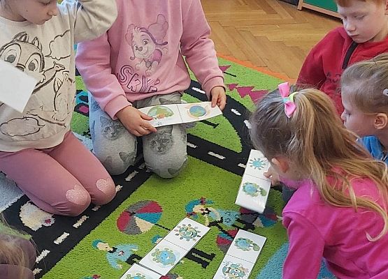 dzieci siedzą na dywanie i układają karty