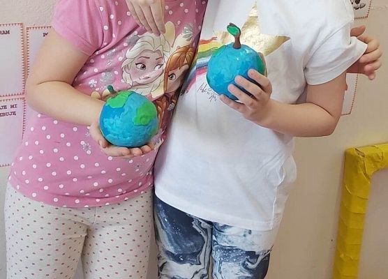 dwie dziewczynki stoją przy tablicy i prezentują swoje niebieskie kule