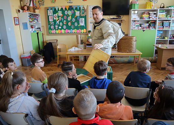 uczniowie siedzą i słuchają pszczelarza
