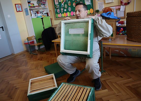 pszczelarz pokazuje dzieciom budowę ula