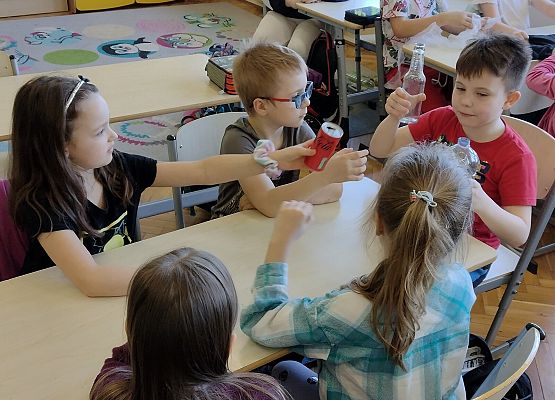 uczniowie porównują wagę plastiku i szkła