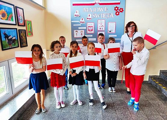 dzieci i nauczycielka i stoją z flagami