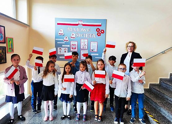 dzieci i nauczycielka i stoją z flagami