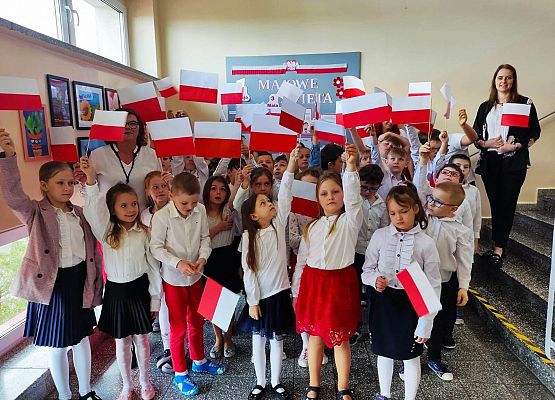 dzieci i nauczycielka i stoją z flagami