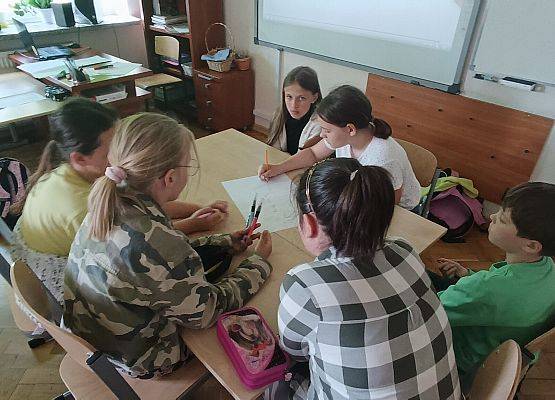 uczniowie siedzą przy stoliku i pracują w grupie