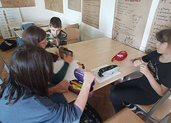 uczniowie siedzą przy stoliku i pracują w grupie