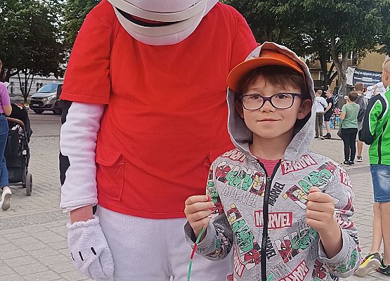 uczeń stoi obok maskotki