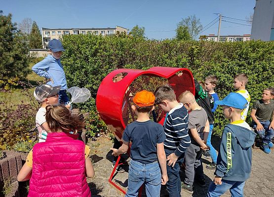 dzieci wrzucają do pojemnika nakrętki od butelek