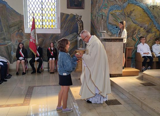uczennica składa dar na ręce proboszcza