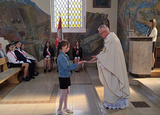 uczennica składa dar na ręce proboszcza