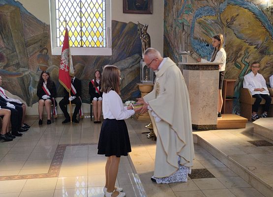 uczennica składa dar na ręce proboszcza