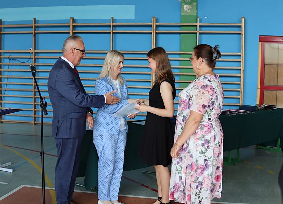 dyrektor i wychowawca wręczają świadectwo uczennicy