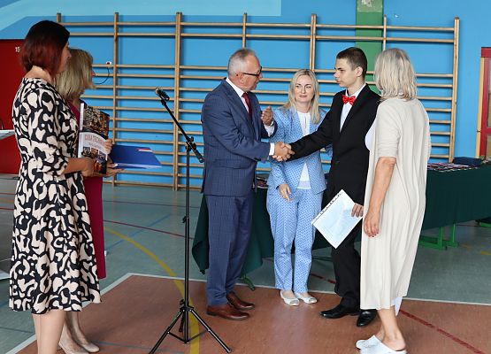 dyrektor i wychowawca wręczają świadectwo uczniowi