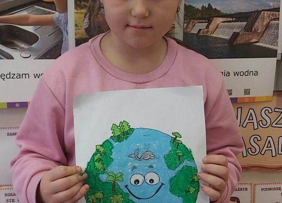 dziewczynka prezentuje swoją pracę plastyczną