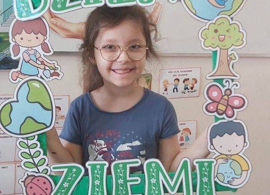 dziewczynka trzyma ramkę z napisem: dzień ziemi