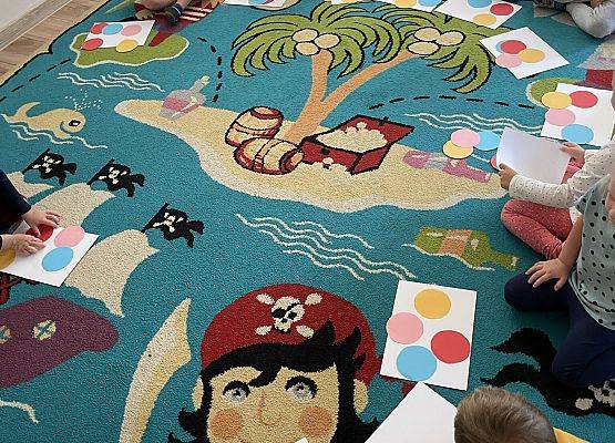 dzieci siedzą na dywanie